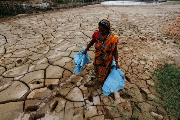 A woman carries tannery waste as she walks through a dried pond at Hazaribagh area in Dhaka